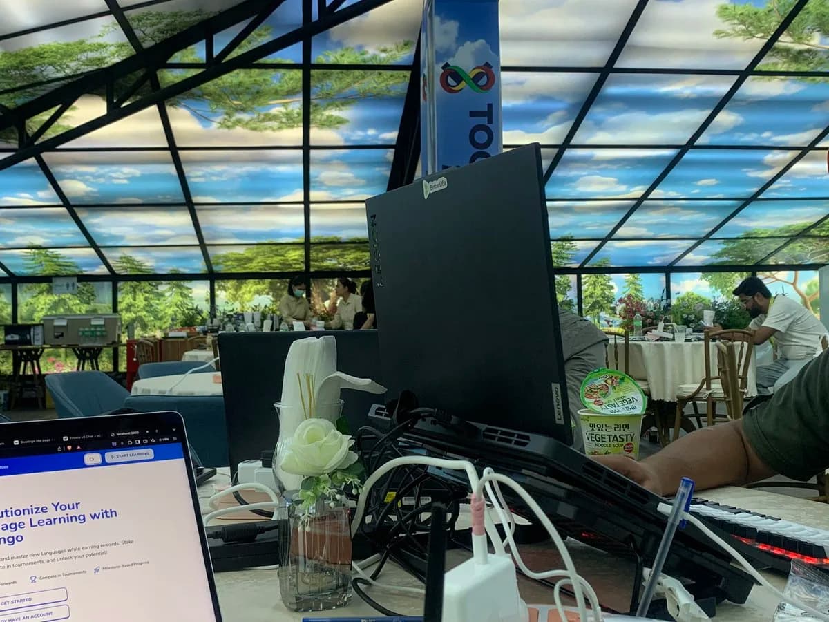A hackathon venue: laptops and cables on a table under a glass roof
